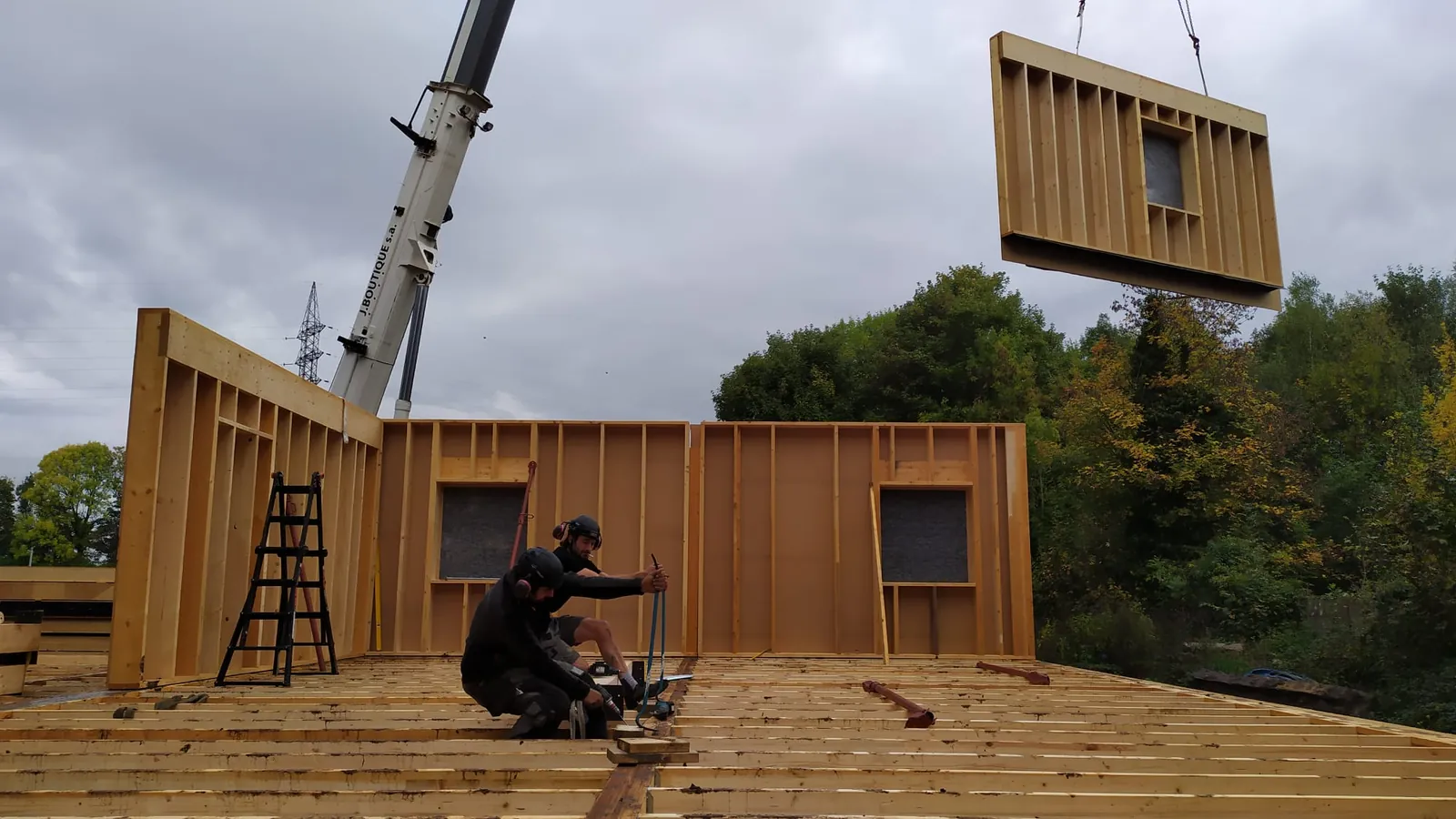 Une grue soulève un plancher en bois préfabriqué